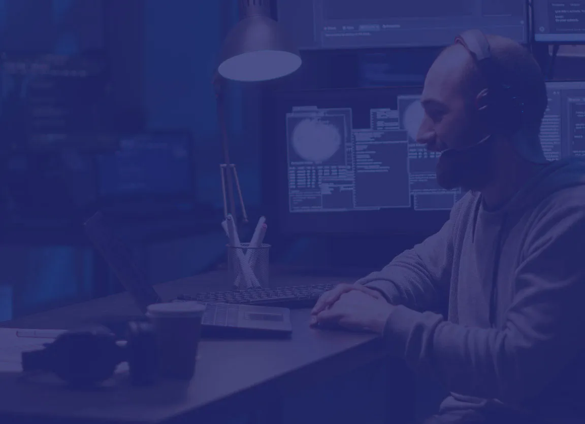 Side view of a bearded man wearing a headset, working at his laptop